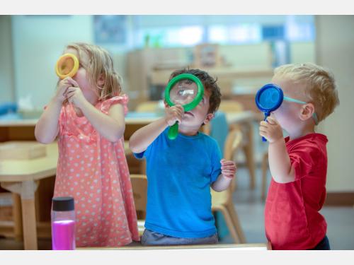 3 preschoolers looking through magnifying glasses