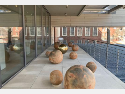 Several terracotta spheres and one gold sphere installed on an enclosed terrace.
