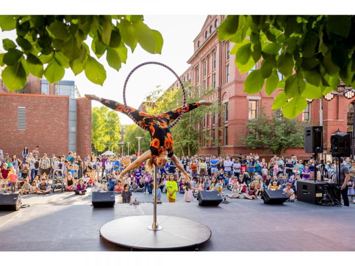 Circus performer doing a handstand with a hoop in front of a large audience. Photo by Caitlin Cunningham Photography LLC.
