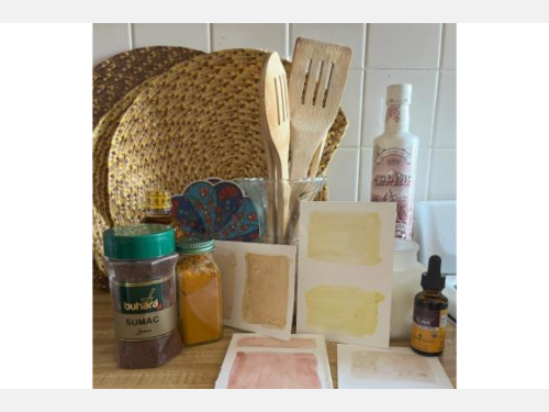 Jars of spices, cooking implements, and colorful paper swatches are set out on a kitchen counter.