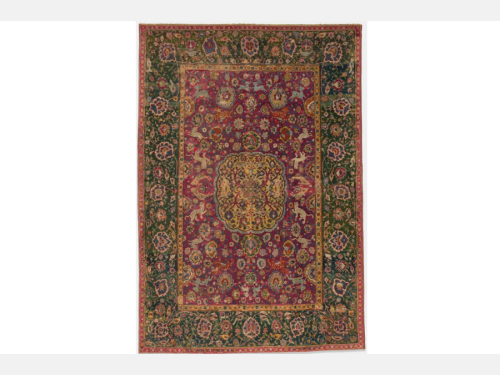 Large, rectangular carpet with animal, medallion, and floral patterns in mainly green, red, blue, and yellow colors.