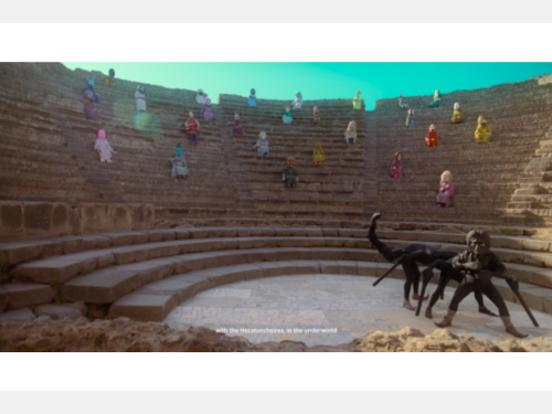 Figures in colorful clothes and masks sit in an amphitheater watching a scorpion-like creature.