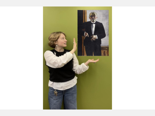 In this photomontage, a young woman stands in front of a green backdrop gesturing toward a painting that appears to float. The painting is of a man in a tuxedo facing the viewer.  