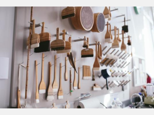 Several conservation tools and instruments, such as wood-handled brushes, hang on a wall. 