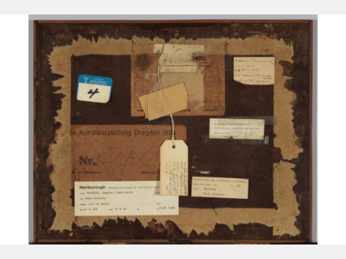 Various labels, stickers, and a tag are attached to a wooden surface.