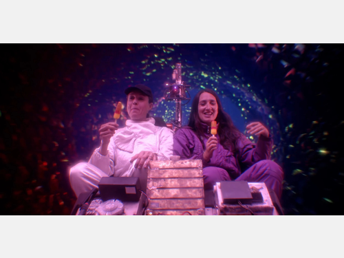 A still from the movie Time Travel is Dangerous! Two people sit side by side eating popsicles with what appears to be the planet Earth in the background. 