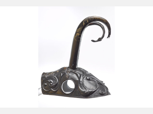 A metal helmet for a horse features two round holes for the horse’s ears and two curved horns on top.