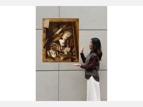 In this photomontage, a young woman stands by a wall gesturing toward a painting that appears to float. It shows a cupboard stuffed with books, papers, and paraphernalia associated with an artist. 