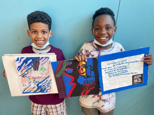 Photo of two students displaying their artwork.