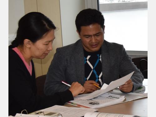 Two adult students complete a worksheet together in class