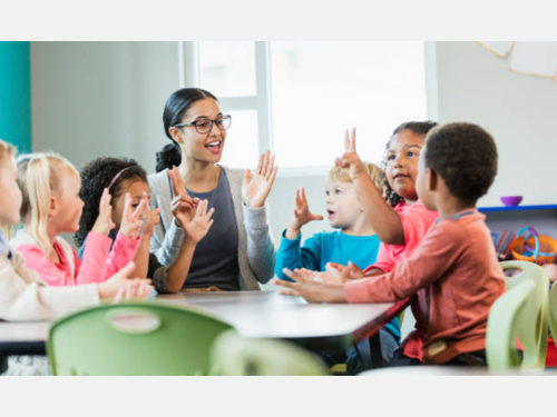 Young students learn to count from a teacher in a classroom.