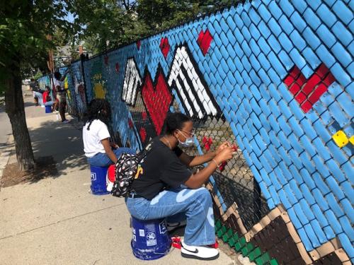 Teens creating a fence-mural at a park in The Port.