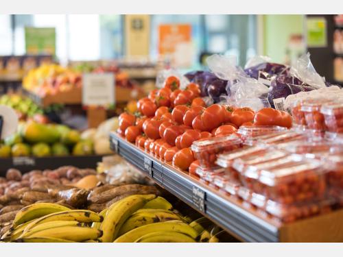 Photo of grocery shelves with tomatoes and plantains.