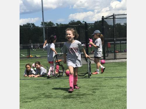 Photo of a group of girls in soccer gear smiling out on the field at Crimson Soccer Camp.