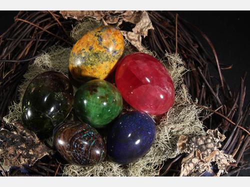 various egg-shaped minerals of different colors in a nest made of lichen and twigs