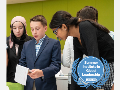 Photo of students in suits huddled together discussing a project at the Summer Institute in Global Leadership.