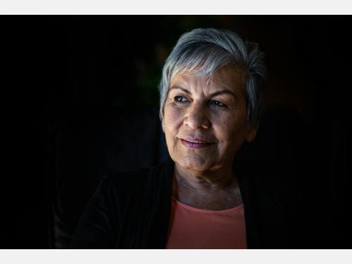 Older adult woman with short hair looking off to the left.