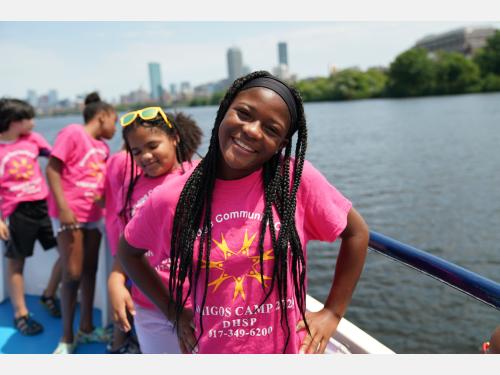 a young girl smiles while on a summer field trip on the Charles River